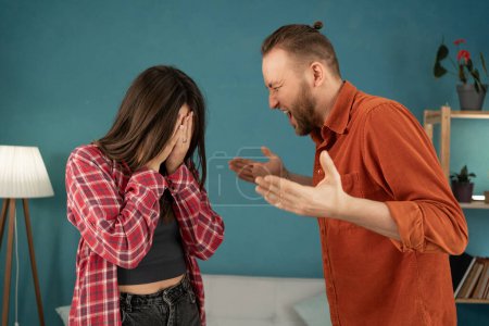 Foto de Joven pareja casada teniendo pelea, marido enojado gritando y haciendo gestos en casa. Romper y divorciarse. Copiar espacio - Imagen libre de derechos