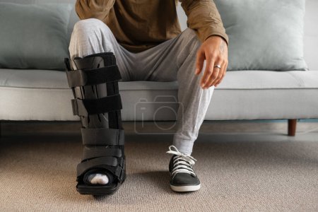 Photo for Close-up of a man with a leg injury using an ankle brace after an accident. Copy space - Royalty Free Image