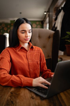 Foto de Mujer atractiva que trabaja con el ordenador portátil mientras está sentado en la cafetería en el interior. Copiar espacio - Imagen libre de derechos