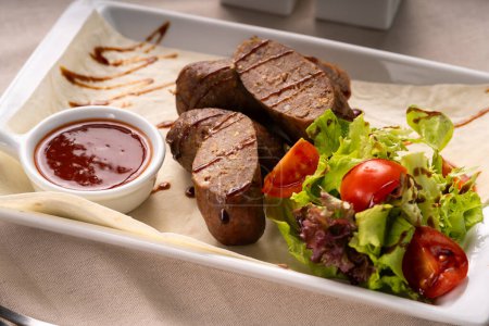 Las salchichas a la parrilla en rodajas o kupaty se sirven con verduras, ensalada y ketchup en un plato blanco. concepto de menú de parrilla