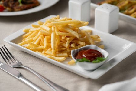 Placa de papas fritas servidas con ketchup en plato blanco. Concepto de alimentos poco saludables