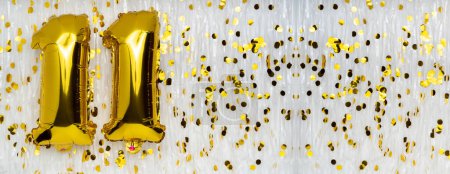 Foil balloon number and digit eleven 11. Birthday greeting card. Golden balloons on white background with copy space. Numerical digit. Anniversary concept.