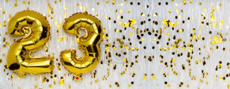 Foil balloon number and digit twenty-three 23. Birthday greeting card. Golden balloons on white background with copy space. Numerical digit. Anniversary concept.