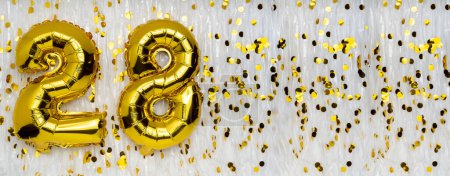 Foil balloon number and digit twenty-eight 28. Birthday greeting card. Golden balloons on white background with copy space. Numerical digit. Anniversary concept.