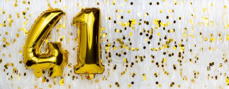 Golden foil balloon number, figure forty-one on white with confetti background. 41th birthday card. Anniversary concept. birthday, new year celebration. banner, copy space.
