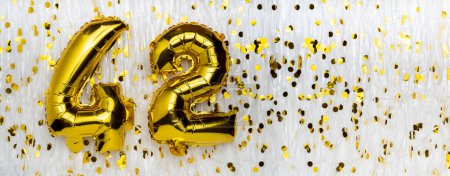 Goldfolie Luftballon-Zahl, Figur zweiundvierzig auf weiß mit Konfetti-Hintergrund. 42. Geburtstag. Jubiläumskonzept. Geburtstag, Neujahrsfeier. Banner, Kopierraum.