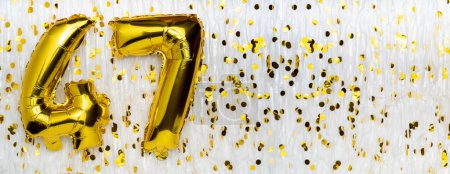 Goldfolie Luftballon-Zahl, Figur 47 auf weißem Hintergrund mit Konfetti. 47. Geburtstag. Jubiläumskonzept. Geburtstag, Neujahrsfeier. Banner, Kopierraum.