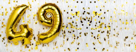 Golden foil balloon number, figure forty-nine on white with confetti background. 49th birthday card. Anniversary concept. birthday, new year celebration. banner, copy space.