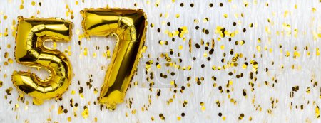 Golden foil balloon number, figure fifty-seven on white with confetti background. 57th birthday card. Anniversary concept. birthday, new year celebration. banner, copy space.