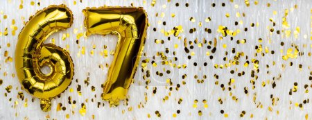 Golden foil balloon number, figure sixty-seven on white with confetti background. 67th birthday card. Anniversary concept. birthday, new year celebration. banner, copy space.