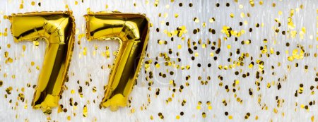 Golden foil balloon number, figure seventy-seven on white with confetti background. 77th birthday card. Anniversary concept. birthday celebration. banner