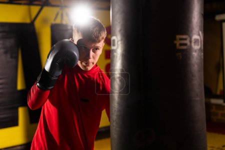 A young boxer is training in the gym on a punching bag. Sports concept. Copy space