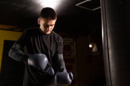 Male boxer putting on boxing gloves in the gym. close-up. Low angle