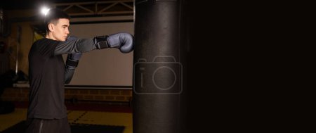 Téléchargez les photos : Boxeur masculin poinçonnant dans la séance d'entraînement de boxe féroce, mettant en valeur la technique de boxe thaïlandaise. Bannière. Espace de copie - en image libre de droit