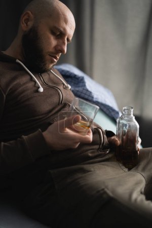 Téléchargez les photos : Alcoolisme, dépendance à l'alcool et concept de personnes. Homme alcoolique dormant sur canapé avec un verre de whisky. Espace de copie - en image libre de droit
