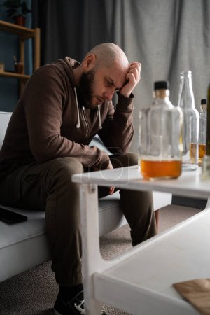 Hombre solitario y deprimido bebiendo whisky y sufriendo dolor de cabeza en casa. Copiar espacio