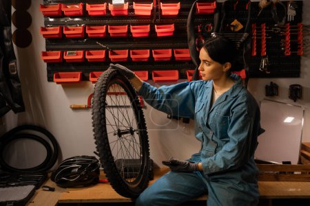 Mujer joven que trabaja en un taller de reparación de bicicletas reparación de rueda de bicicleta. Copiar espacio