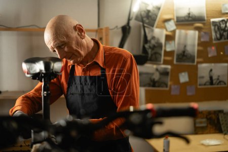 Photo for Senior male worker repairing bicycle. Bike workshop or garage interior. Copy space - Royalty Free Image