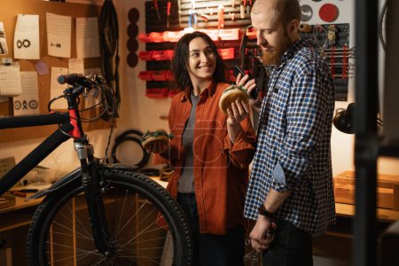 Hombre y mujer reparando bicicleta moderna en garaje o taller, almuerzo en el trabajo. Copiar espacio