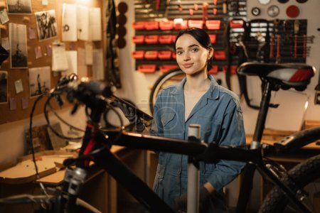 Photo for Portrait of Beautiful young female mechanic enjoying while repairing bicycles in a workshop. Copy space - Royalty Free Image