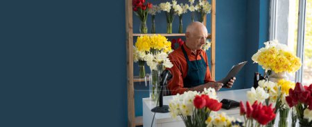 Hombre mayor florista estudiando papeles. hay bouqeuts de flores a su alrededor
