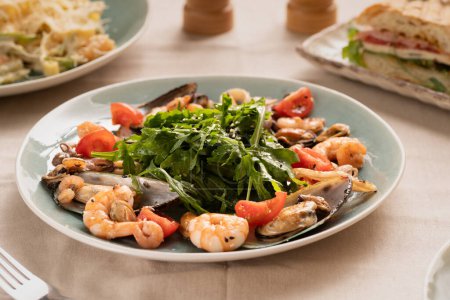Téléchargez les photos : Salade de moules, palourdes, roquette et tomate servie dans un restaurant. Alimentation au céto et concept d'alimentation saine - en image libre de droit