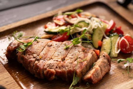 Grilled sirloin beef meat steak with vegetables on wooden board. close-up. Top view. Copy space