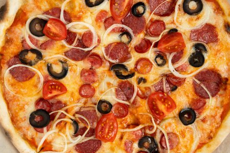 Großaufnahme von Pizza mit Wurst, Oliven und Tomaten auf dem Tisch. Kopierraum