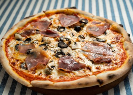 Traditionelle italienische Pizza mit Speck und Champignons, in Scheiben geschnitten, aus nächster Nähe. Italienisches Pizzeria-Konzept