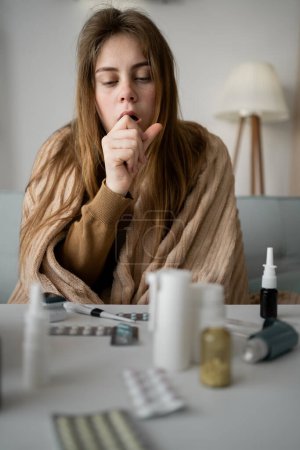 jeune femme malade bouleversée assise sur le canapé à la maison couverte d'une couverture toussant intensément, fille malade avec des symptômes de grippe,