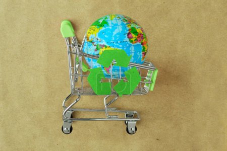 Earth planet in green shopping cart with recycle symbol on recylced paper - Concept of ecology and responsible shopping