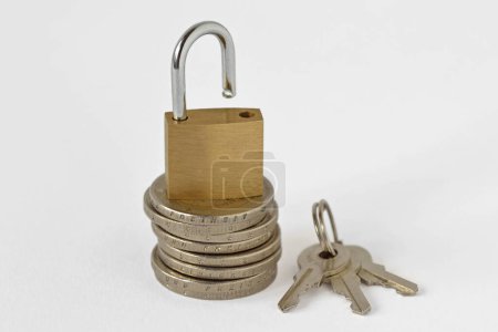 Foto de Candado abierto en pila de monedas con llaves sobre fondo blanco - Concepto de seguridad financiera - Imagen libre de derechos