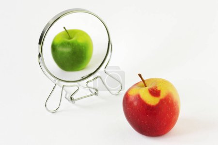 Foto de Manzana roja mirándose en el espejo y viéndose a sí misma como una manzana verde - Concepto de daltonismo y daltonismo - Imagen libre de derechos