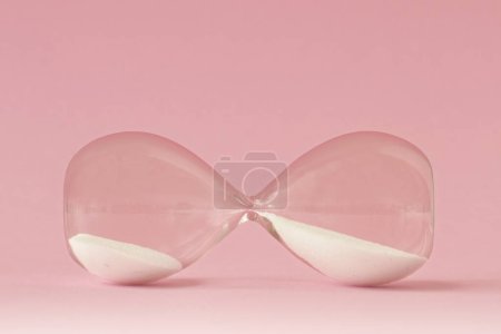 Photo for Hourglass lying on pink background - Concept of time and woman - Royalty Free Image