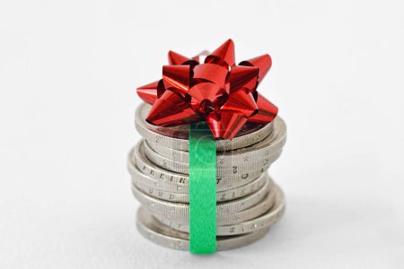 Téléchargez les photos : Empilement de pièces en euros emballées avec ruban et noeud cadeau - Concept d'économie et cadeau d'argent - en image libre de droit