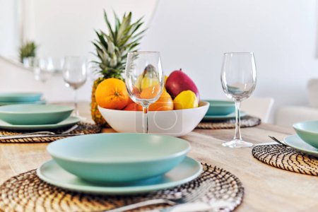 Téléchargez les photos : Gros plan sur une table à manger fruits tropicaux dans un bol servi avec du verre vide et des assiettes pour le dîner de famille à la maison - en image libre de droit