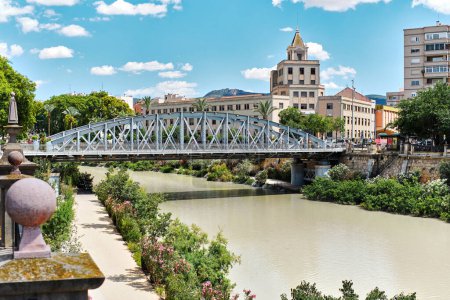 Téléchargez les photos : Nouveau pont en fer, pont métallique parabolique traversant la rivière Segura dans le centre de la ville de Murcie à la journée ensoleillée d'été sur fond d'architecture et de ciel bleu nuageux. Espagne - en image libre de droit