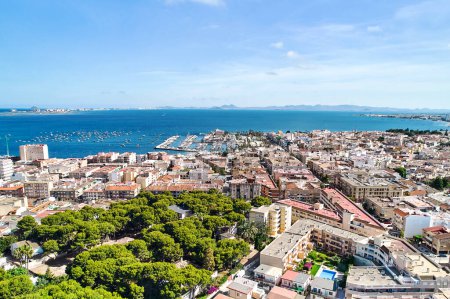 Photo for Panoramic daytime view of San Pedro del Pinatar townscape roofs and Mediterranean Sea view with marina port moored nautical vessels, drone point of view, aerial shot. Travel and tourism concept - Royalty Free Image