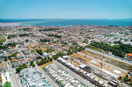 Photo for Panoramic daytime view of San Pedro del Pinatar townscape roofs and Mediterranean Sea view with marina port moored nautical vessels, drone point of view, aerial shot. Travel and tourism concep - Royalty Free Image