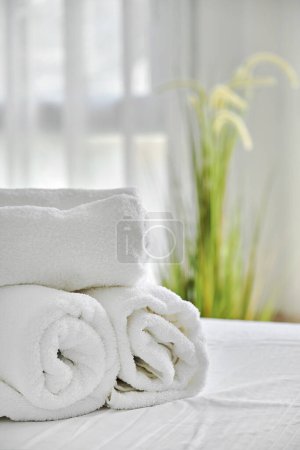 Foto de Tres toallas blancas dobladas en la cama en el dormitorio acogedor, vista de cerca. Alojamiento, vacaciones y concepto de higiene - Imagen libre de derechos