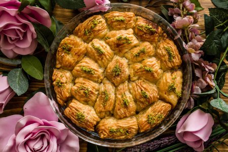 Turkish pistachio pastry dessert, Baklava presented on a round tray surrounded by roses.