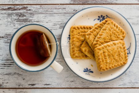 Photo for Assortment of biscuits on a plate, served with a cup of tea. - Royalty Free Image
