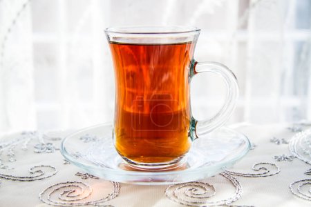 Photo for Turkish tea in an ornate glass, beverage on an embroidered cloth. - Royalty Free Image