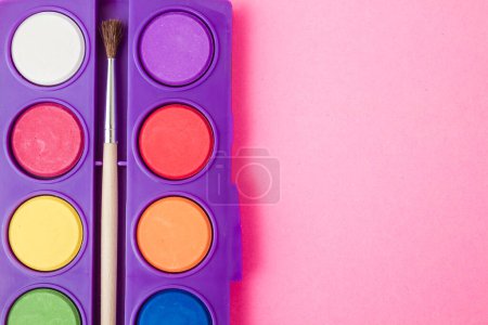 Photo for Opened watercolor paint set in a purple box, revealing vibrant colors of paint in circular pans. - Royalty Free Image