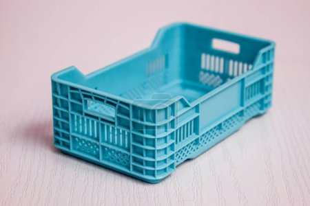 Foto de Caja de plástico de un solo color azul claro colocada sobre un fondo rosa. - Imagen libre de derechos