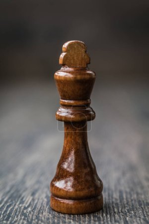 Pieza de ajedrez rey negro sobre una mesa de madera, símbolo de estrategia y táctica.