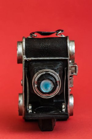 Photo for Decorative nostalgic camera figurine on red background, vintage charm, unique perspective. - Royalty Free Image