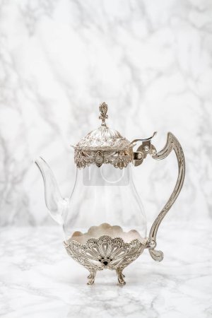 Photo for Exquisite glass and metal jug displayed on elegant white marble. - Royalty Free Image