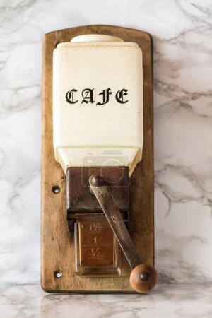 Vintage wooden coffee grinder against white wooden background.