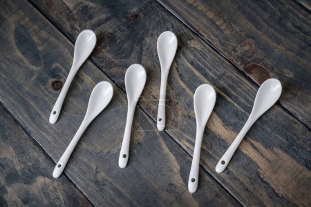 Simple white tea spoons arranged on a blue wooden background.